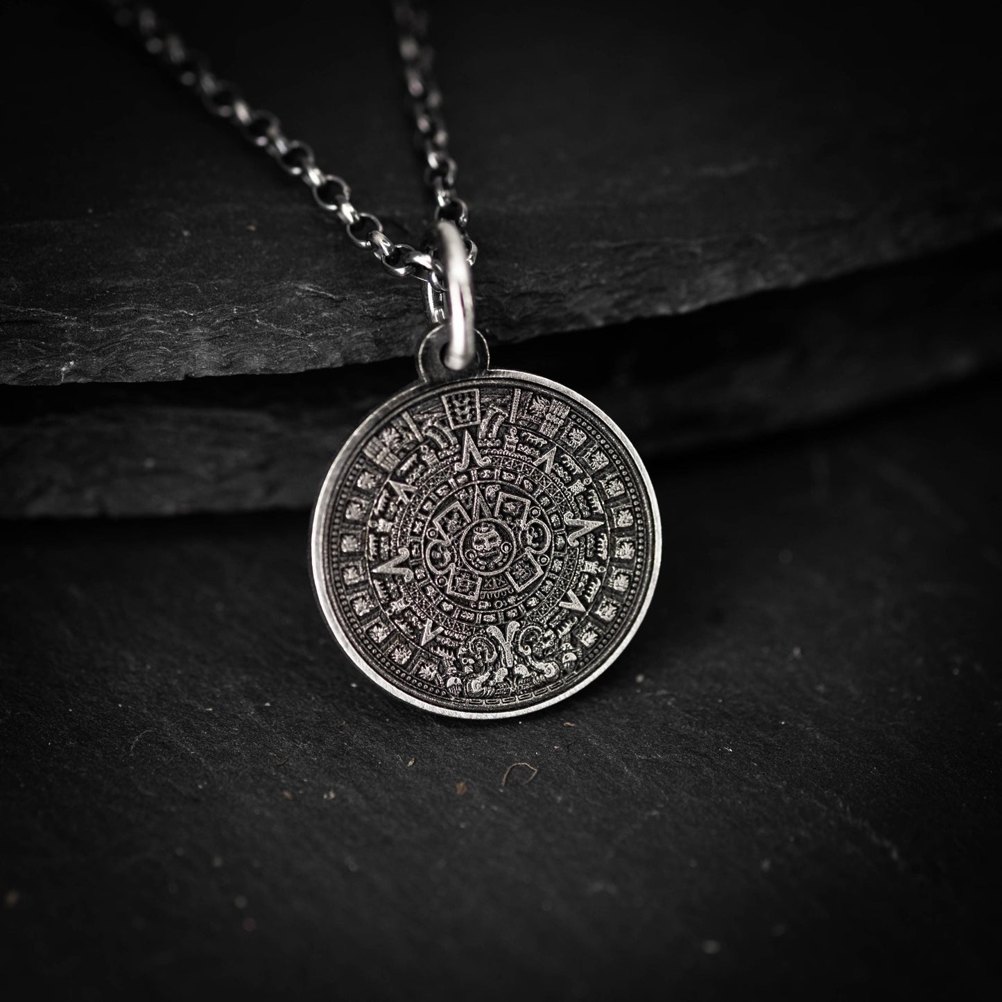 A silver pendant necklace with a circular pendant featuring an intricate design.