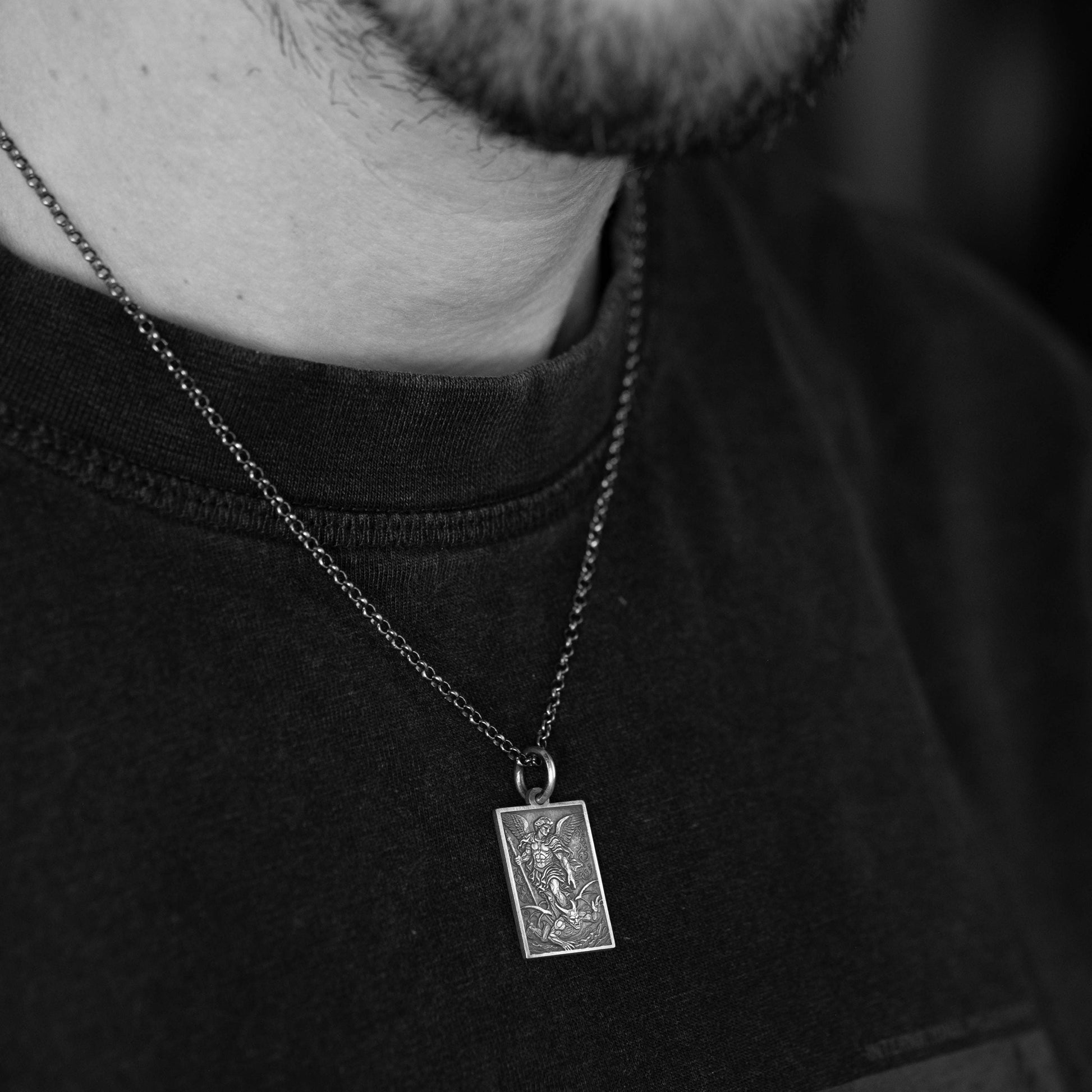 A close-up of a person wearing a necklace with a pendant, which appears to be a religious or symbolic piece.