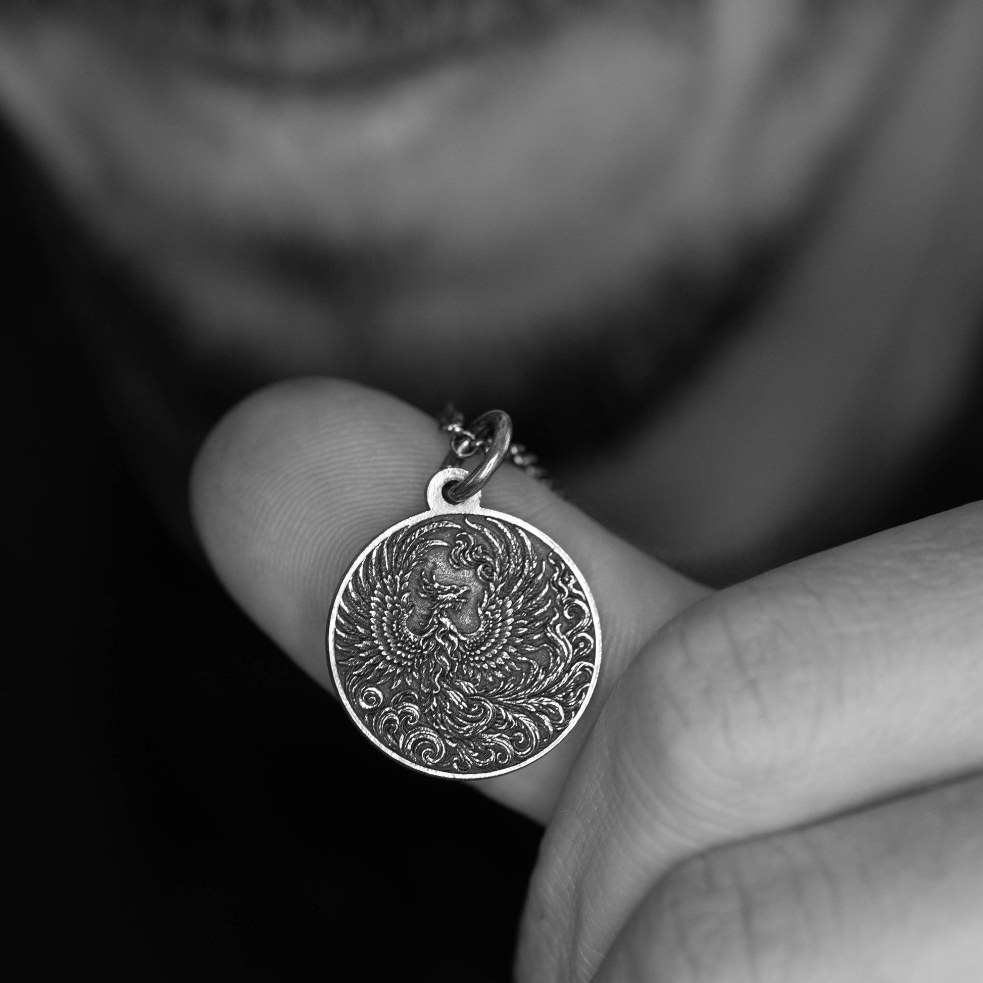 A person's hand holding a small, circular pendant with an intricate design.