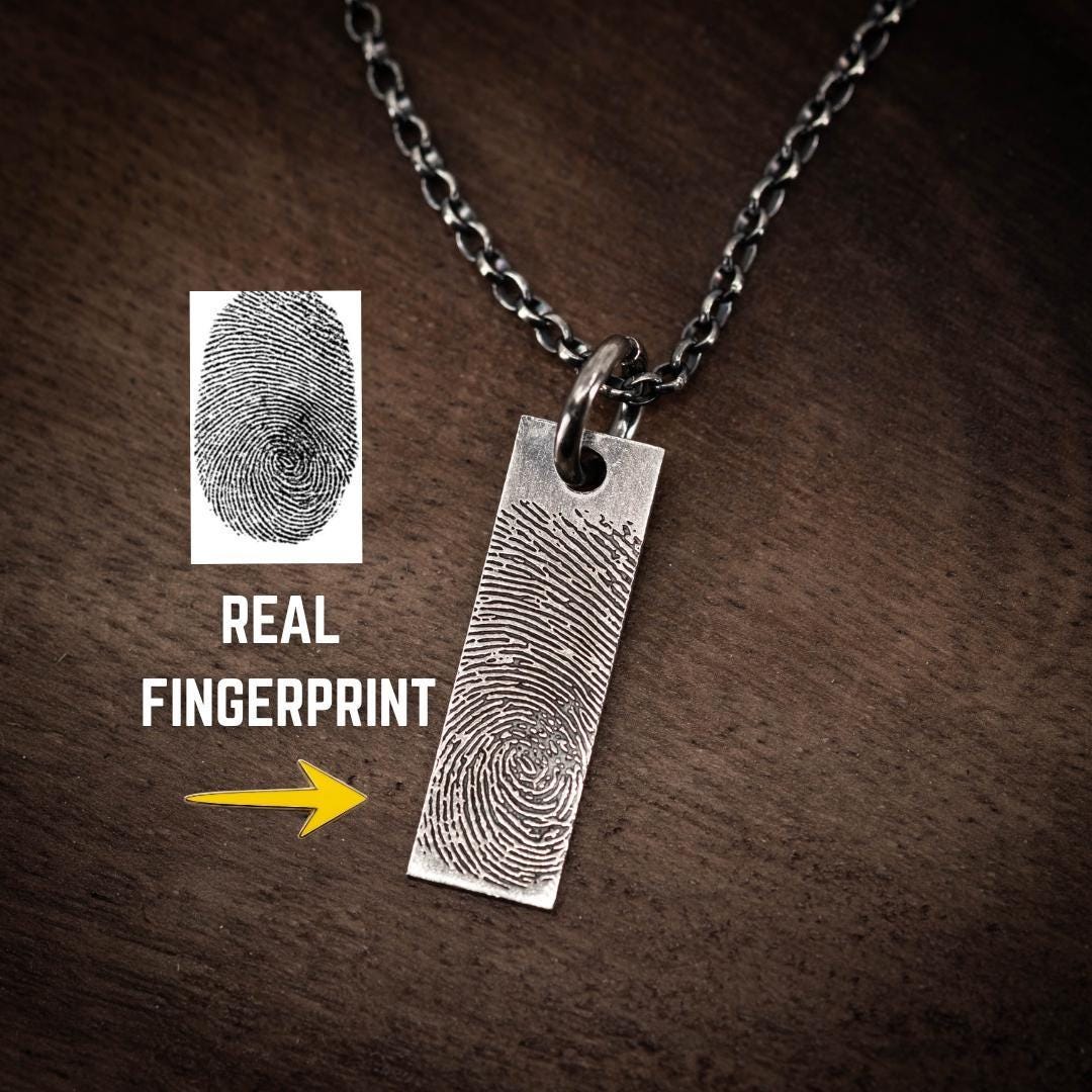 a silver necklace with a rectangular pendant that resembles a fingerprint.