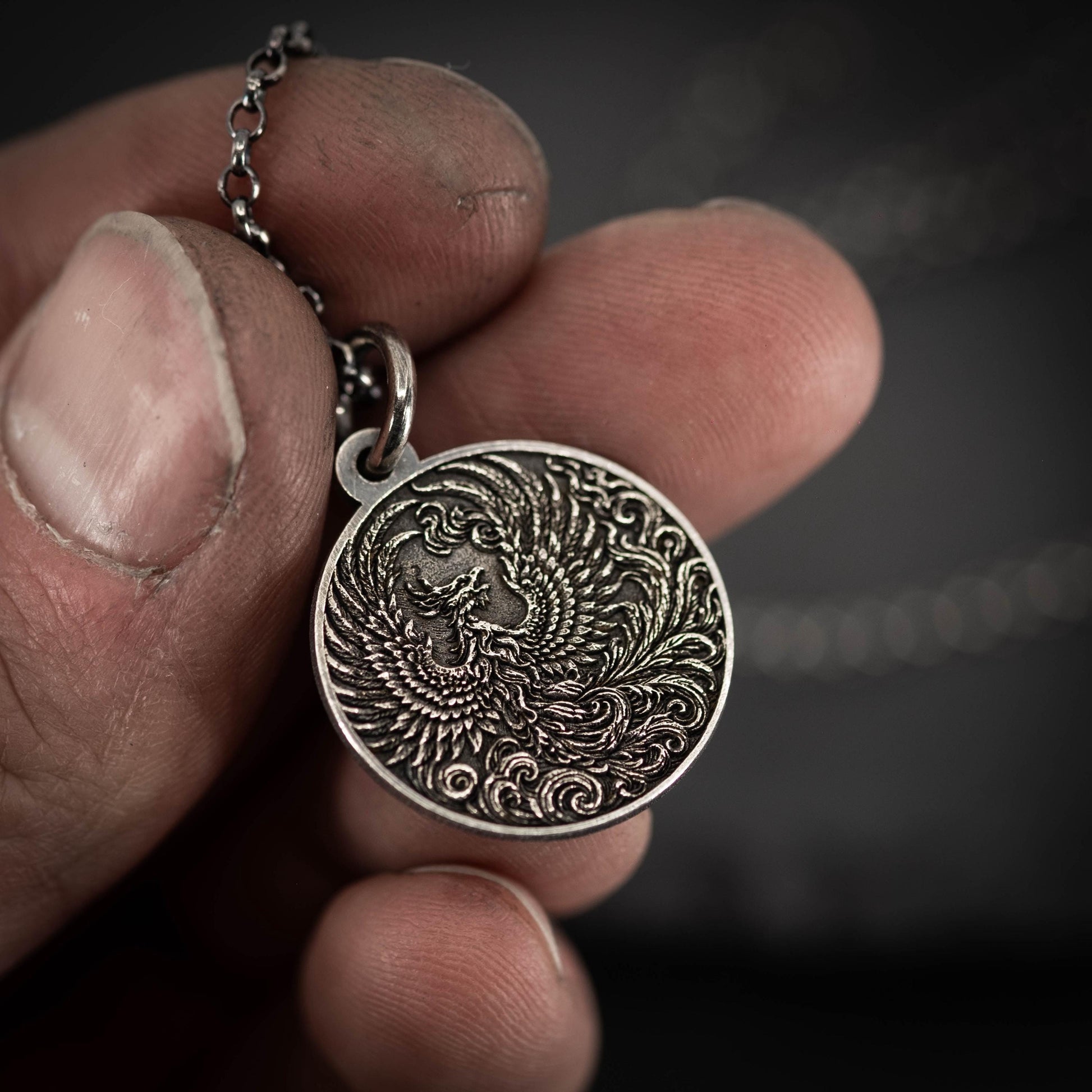 A close-up image of a person's hand holding a circular pendant with an intricate design, possibly a symbol or emblem.
